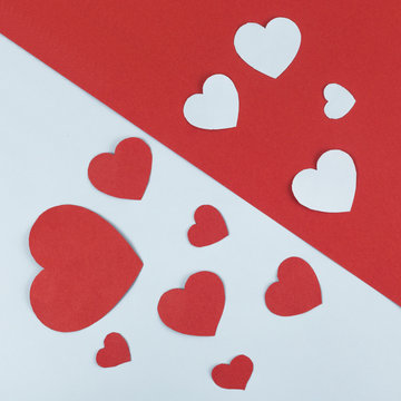 Group of paper Hearts layed on devided white and red background.