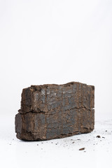 Peat briquette on white background, alternative fuels, place for text