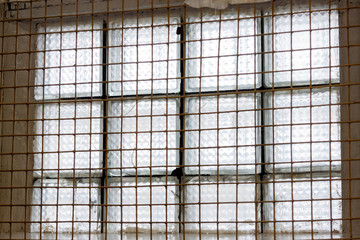 A look at the window of the prison cell from the inside. Metal lattice on the window
