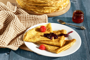 Thin pancakes on a blue table and on a plate