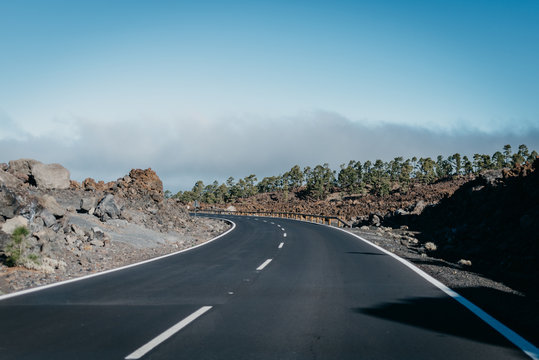 Highway goes through the volcanic rocks near the clouds. Teide National Park. Tenerife