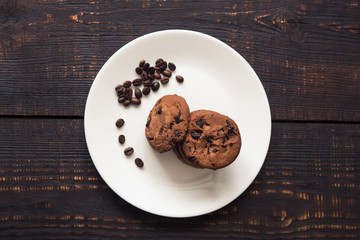 chocolate chip cookies on a white plate with coffee beans on dark wooden table