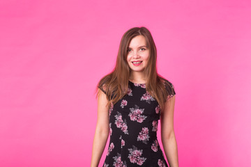 Young woman in a dress on a pink background