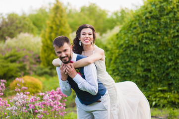 Bride hugs groom from the back on nature green background