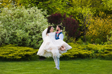 Smiling groom hold her bride in hands