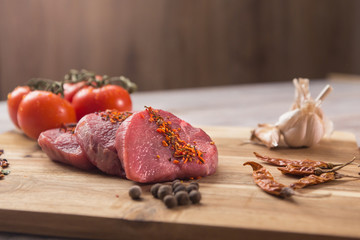 beef steak with vegetables and spices on a cutting Board, a white wooden table