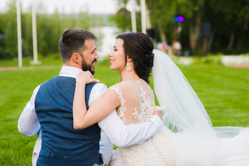 Smiling wedding couple from the back outdoors