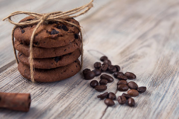 chocolate chip cookies tied with twine with coffee beans and cinnamon stick on white wooden table