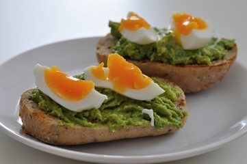 cereal bread with avocado spread and egg on white plate, healthy breakfast, vegetarian food