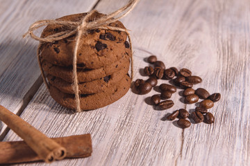 chocolate chip cookies tied with twine with coffee beans and cinnamon stick on white wooden table