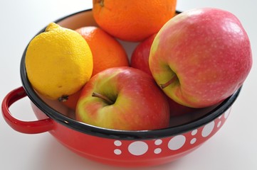 red vintage bowl with white dots including fresh fruits like apples, oranges, lemon, healthy food, vegan diet - 191789389