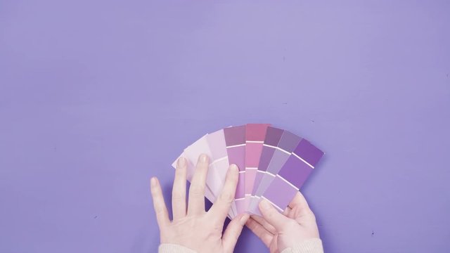 Hand holding paint swatches with shades of violet colors