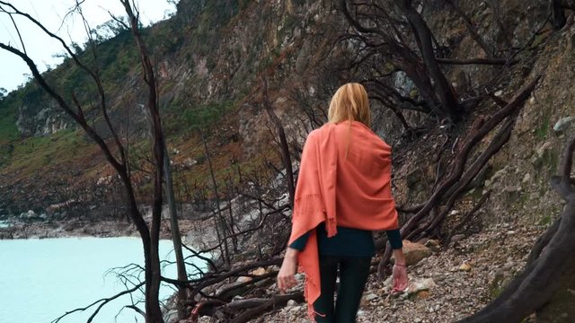 Young caucasian woman walking around Kawah Putih White Crater lake