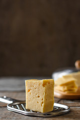 a piece of hard cheese and a grater on a wooden table