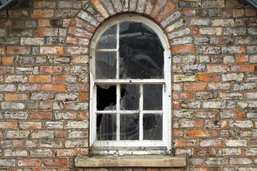 Broken windows in a dilapidated brick built house
