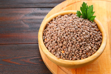 Red lentils in a wooden bowl on a wooden table.