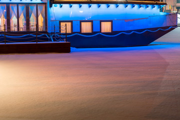 Colorful ship with festive lights frozen in river. Restaurant on water at winter. Atmospheric feeling in city Jelgava at Christmas time.