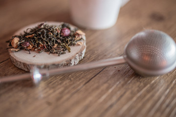 Tea on a log of wood with a cup and a teaball