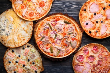 Six different pizza set for menu on wooden table. Italian food. Pizzas with salami and ham, quattro formaggi and pear, salmon, chicken and gherkins, chicken fillet and corn, bacon and olives, top view