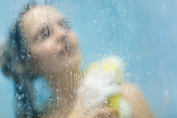 Rear view of unrecognizable woman wash her body with sponge in bathroom, takes shower alone, poses at bathroom in shower cabine, feels relaxed and relief. Lifestyle and recreation concept