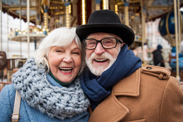 Portrait of happy mature couple having fun in city. They are looking at camera and laughing
