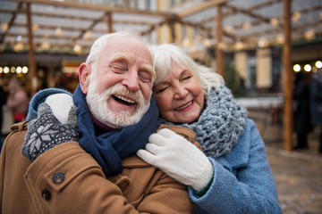 We are so happy together. Portrait of glad old loving couple hugging with fondness. They are standing on street and smiling