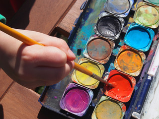 Kind malt mit Wasserfarbe
