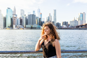 Back of young woman outside outdoors in NYC New York City Brooklyn Bridge Park by east river,...