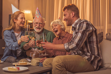 Laughing relatives having party in apartment. They tasting champagne while talking with each other. Party concept