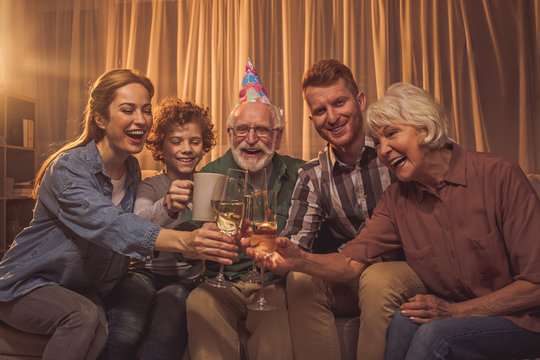 Portrait of cheerful relatives tasting glasses of alcohol while having party at home. Event concept