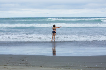 Very Brave Small 4 or 5 Years Girl in preschool age walking in the Ocean with bright blue water, Pacific Ocean, Oregon Coast, USA, Family Vacation