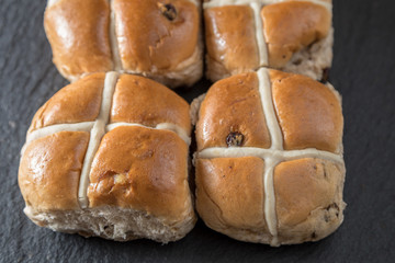 Four traditonal Easter hot cross buns on a grey slate
