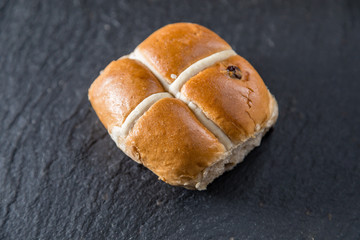 One Easter hot cross bun on a grey slate