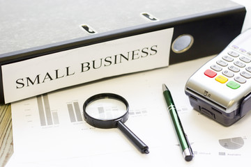 Modern technology and people concept - pos terminal and small business documents. Rough bords background. Closeup