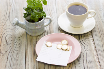 Pay restaurant bill. Bill, bank card, coins near cup of coffee on light wooden table top view