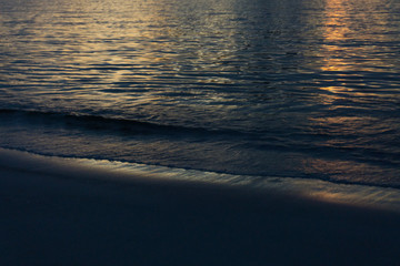 Dusk on the beach. Reflection of the sun in the calm sea. 