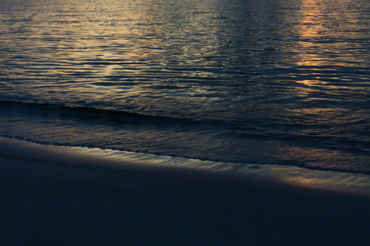 Dusk on the beach. Reflection of the sun in the calm sea. 