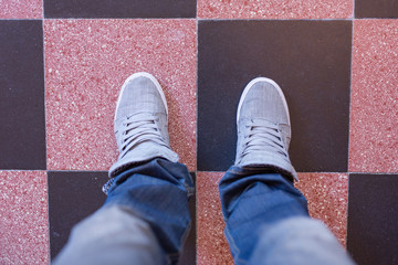 Male feet in jeans and sneakers in the kitchen