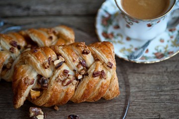 Danish pastry maple pecan with nuts and a cup of coffee, breakfast
