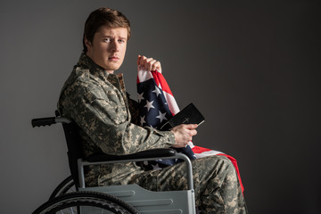 Sad disabled soldier sitting in invalid chair and looking at camera with frustrated look. He is...