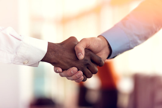 Closeup Of White And Black Shaking Hands Over A Deal