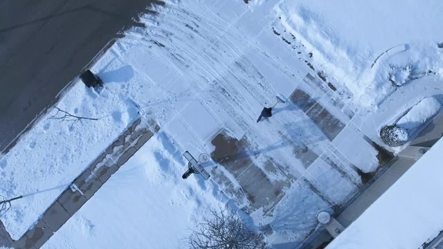 4k Aerial man shoveling snow from his driveway after winter storm