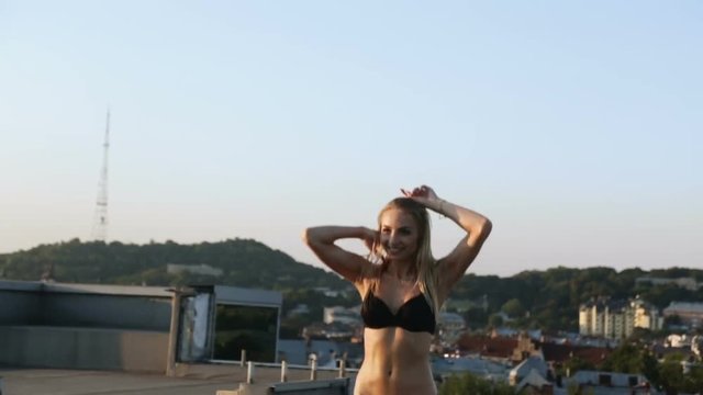 pretty nice blonde woman swimming suit jumping trampoline roof urban landscape background portrait full view sun light summer sunshine sport activity leisure leap recreation cardio gym fut fashion