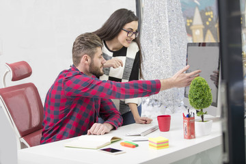 Couple of young designers working at modern office, two coworkers discussing fun project over a laptop,