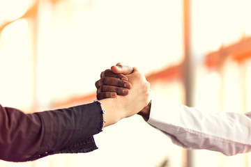 Closeup of White and Black shaking hands over a deal