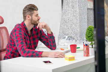 Concentrated on work. Concentrated young beard man working on laptop while sitting at his working...