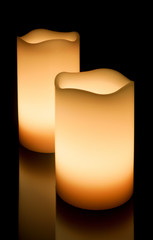 Two LED candles on a reflective surface