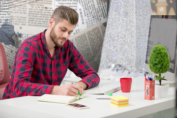 Concentrated on work. Concentrated young beard man working on laptop while sitting at his working...