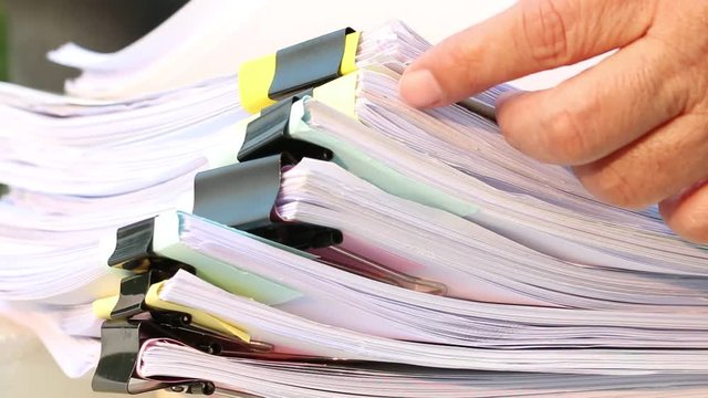 Businesswoman hands working on Stacks of documents files for finance in office. Business report papers or Piles of unfinished document achieves with black clip paper. Concept of Business Annual Report