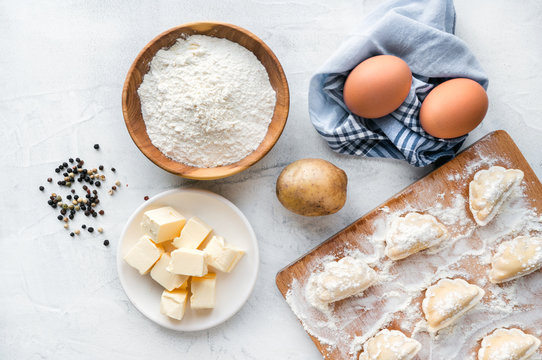 Top view eggs, dough, potato, flour and rolling-pin on concrete background. Process of cooking vareniki - traditional slavic dumplings.